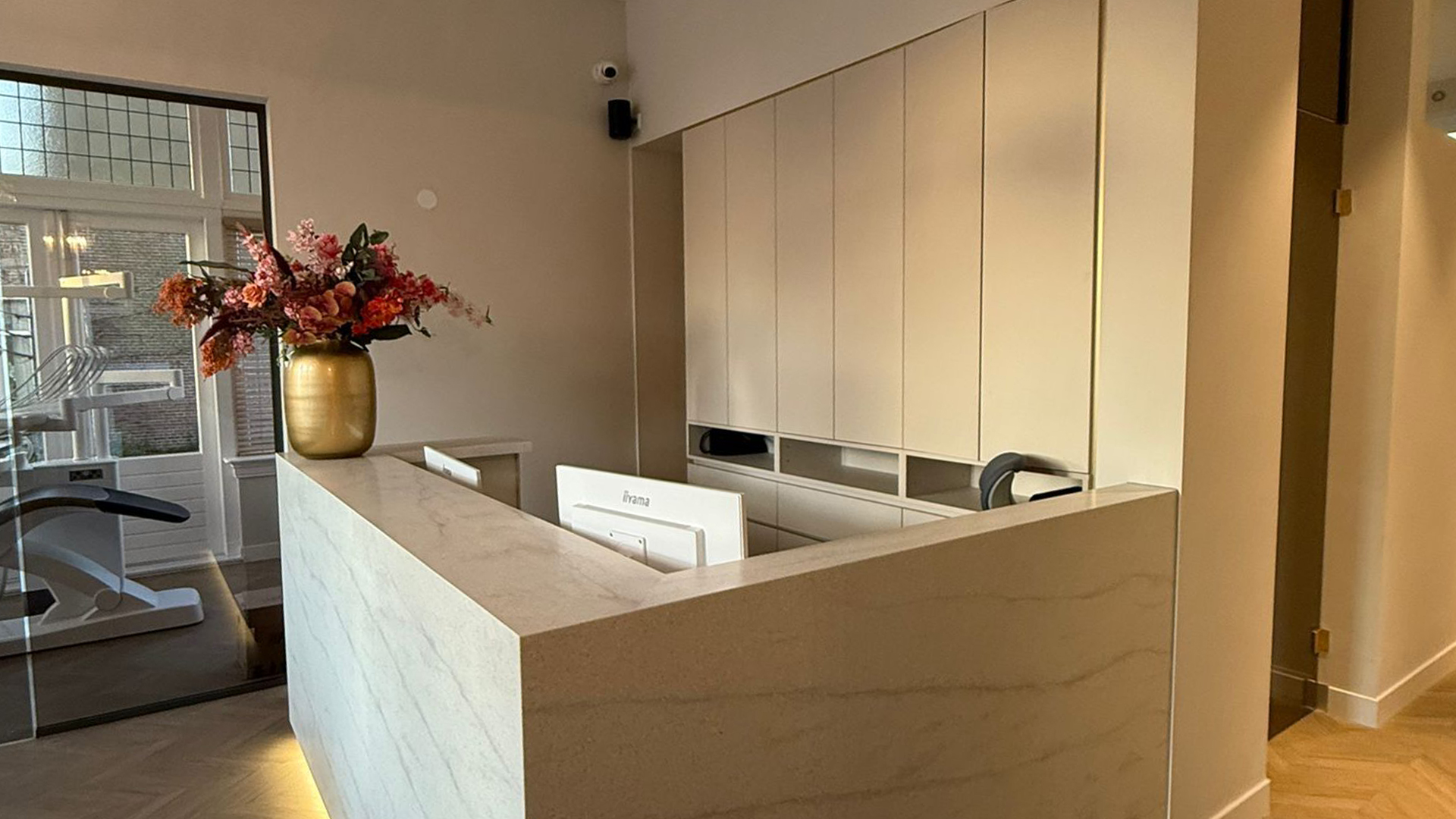Receptiebalie met gouden vaas en bloemen in moderne tandartspraktijk Alkmaar Centrum