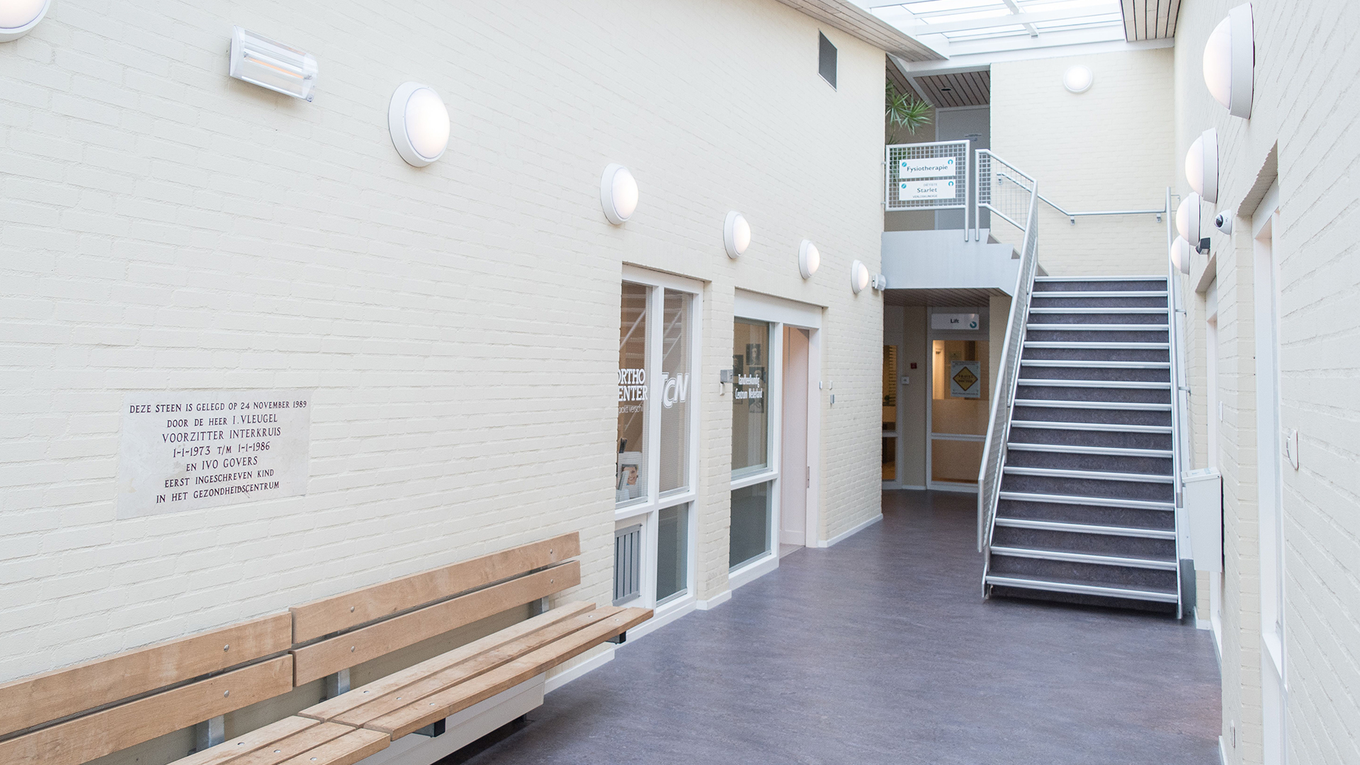 Verlichte gang met houten bank en trap bij Tandarts Alkmaar Daalmeer