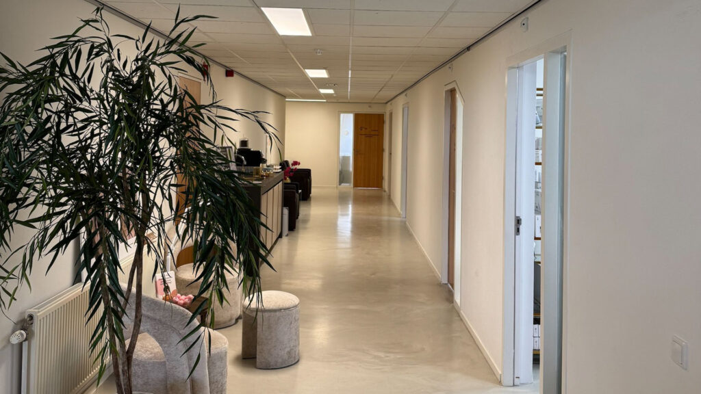 Gang op eerste verdieping met wachtruimte, planten en houten deuren bij Tandarts Alkmaar Oudorp