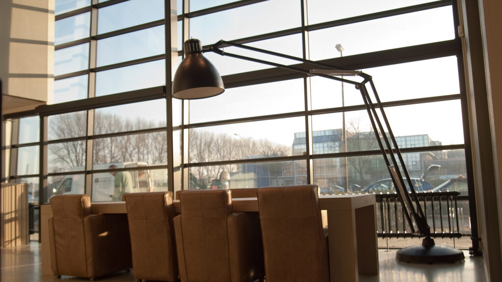Zonnige kamer met grote lamp en leren stoelen bij Tandarts Alkmaar Oudorp