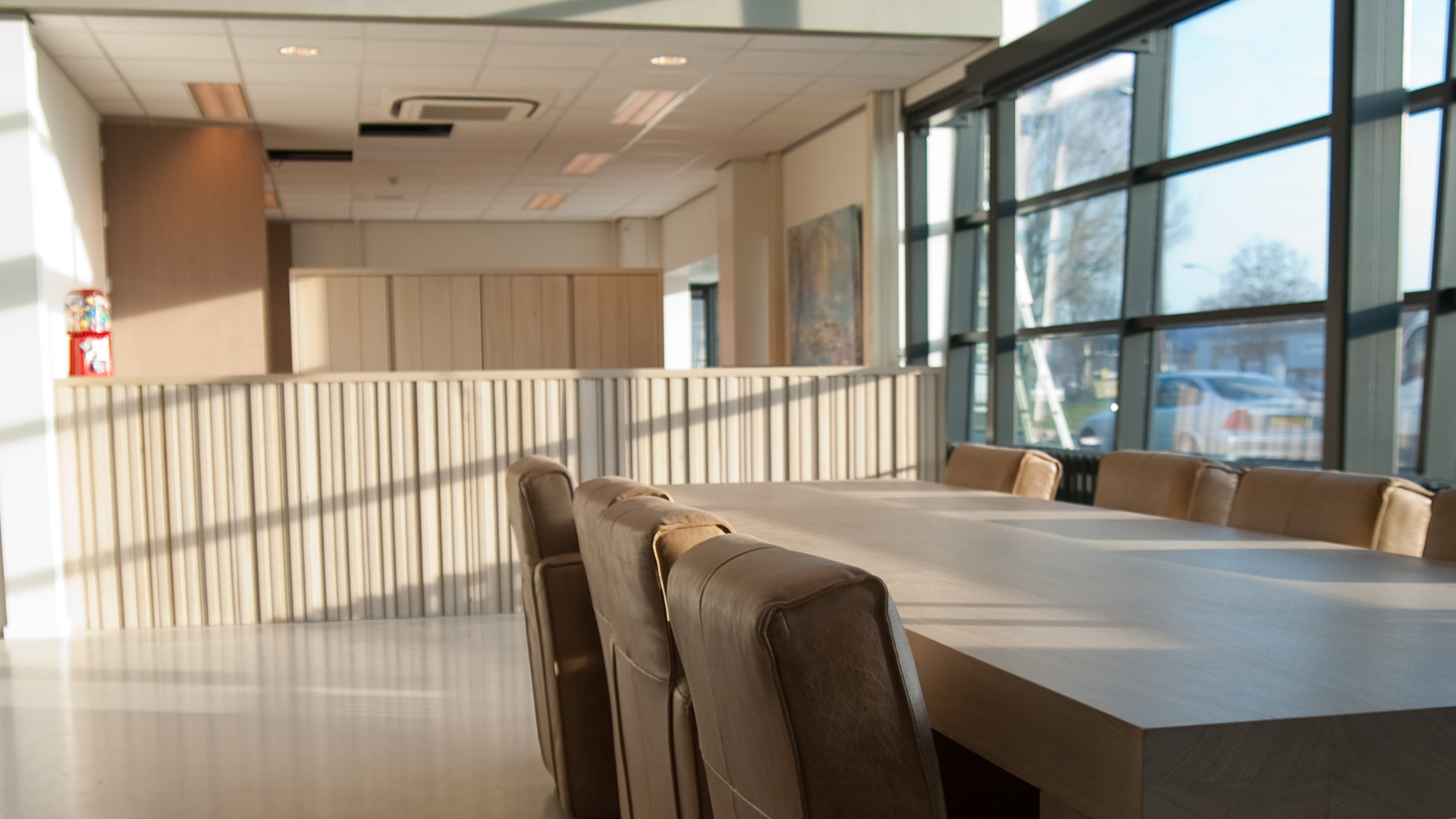 Wachtkamer met leren stoelen en houten wand, verlicht door grote ramen bij Tandarts Alkmaar Oudorp