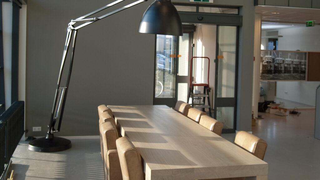 Vergadertafel met leren stoelen en grote lamp bij Tandarts Alkmaar Oudorp