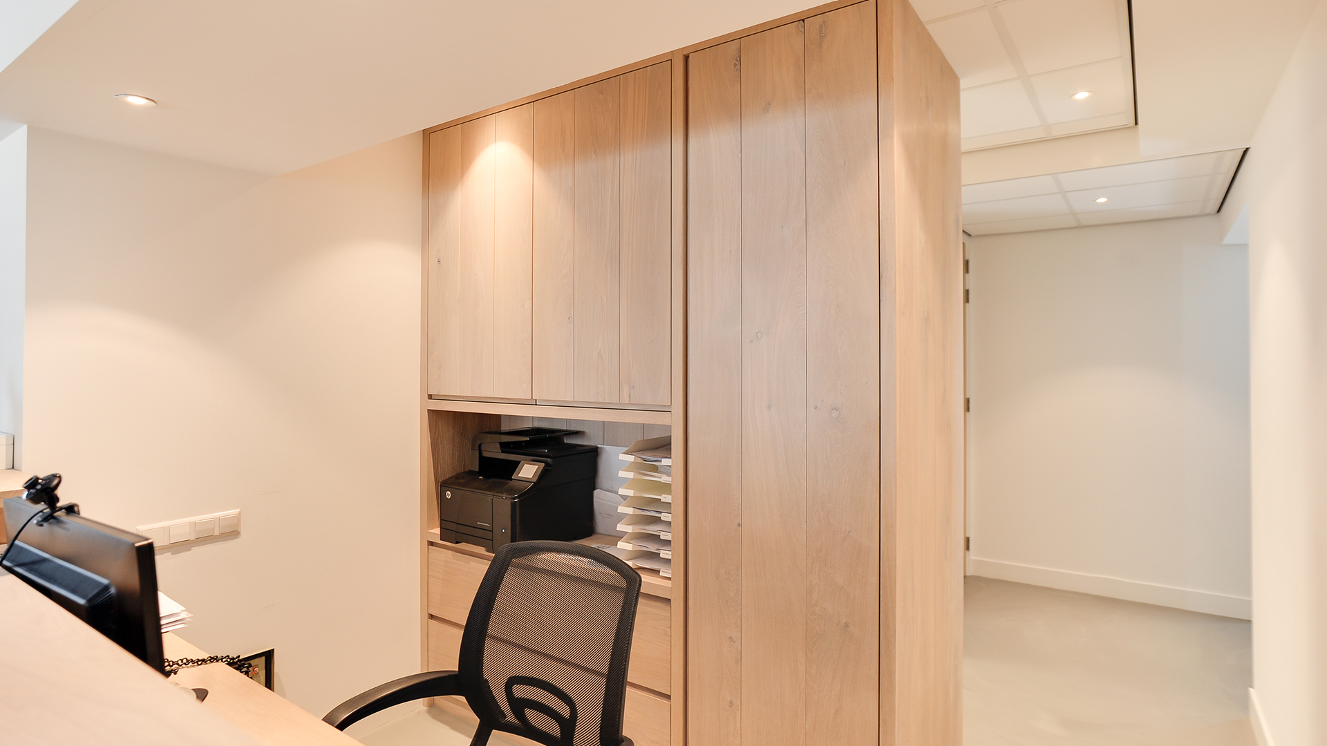 Werkplek achter balie met houten kastenwand bij Tandarts Heerhugowaard
