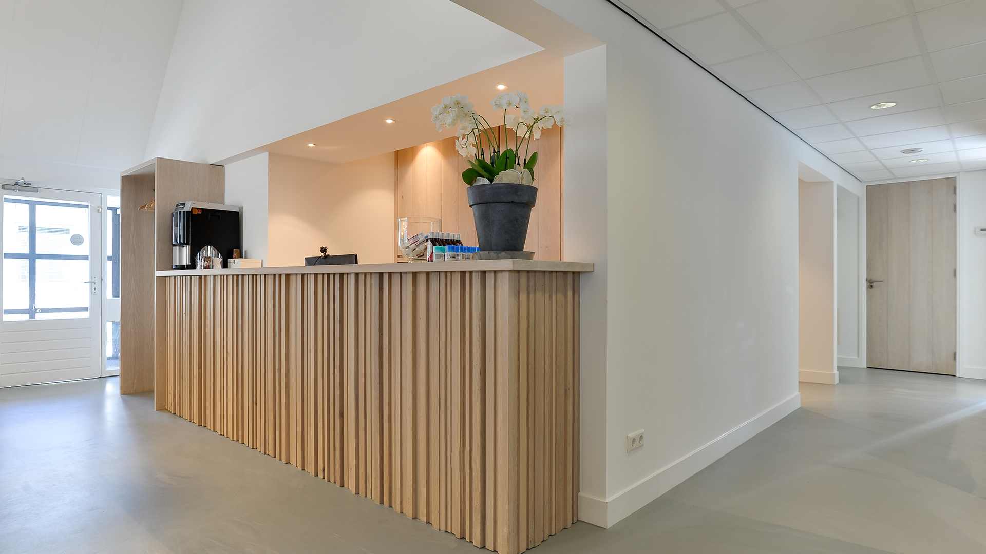 Balie met houten lamellen en witte muren bij Tandarts Heerhugowaard