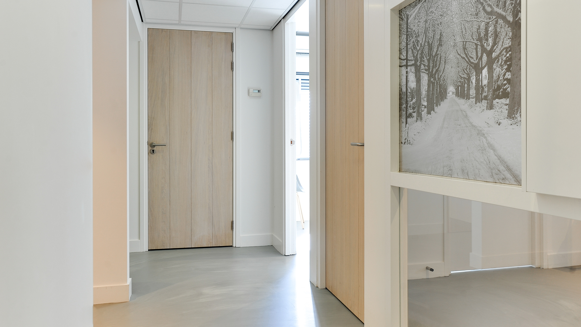 Hal met houten deuren en winterse wanddecoratie bij Tandarts Heerhugowaard
