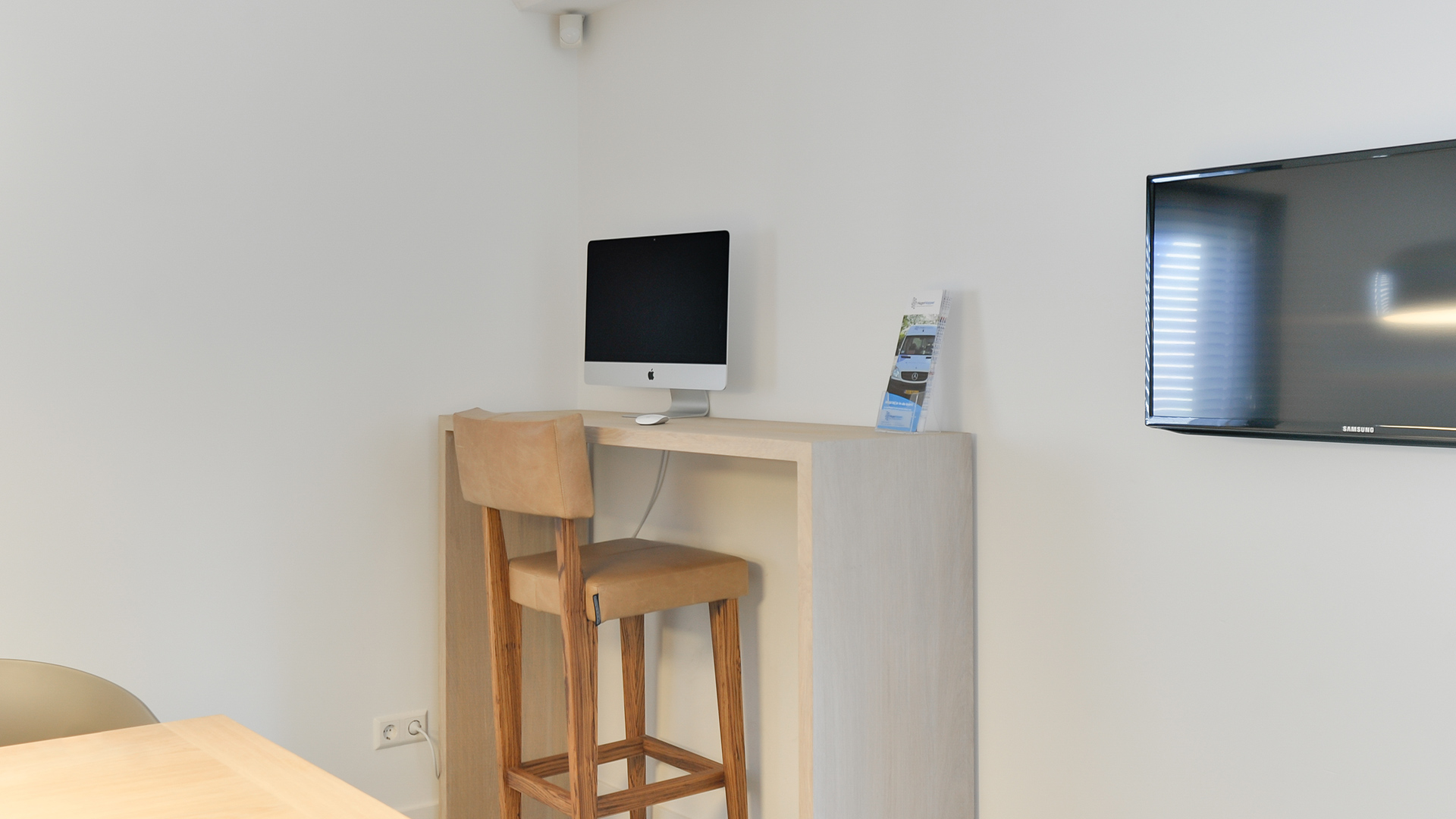 Computerhoek met houten tafel en iMac in wachtruimte van Tandarts Heerhugowaard