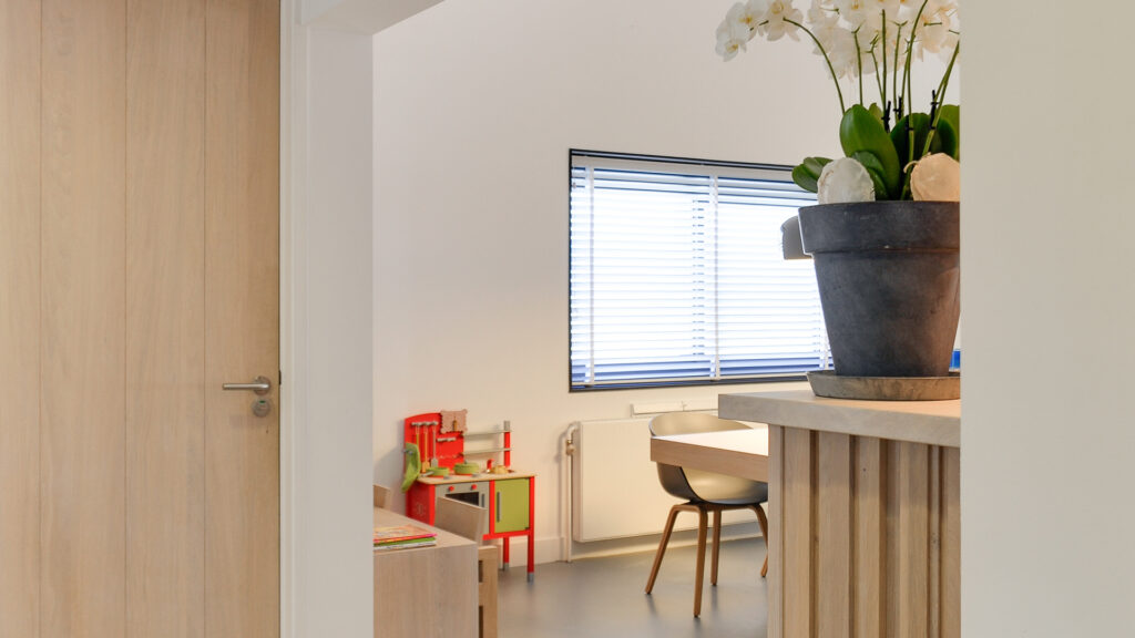 Zijkant van wachtruimte met kinderhoek en bloemen bij Tandarts Heerhugowaard