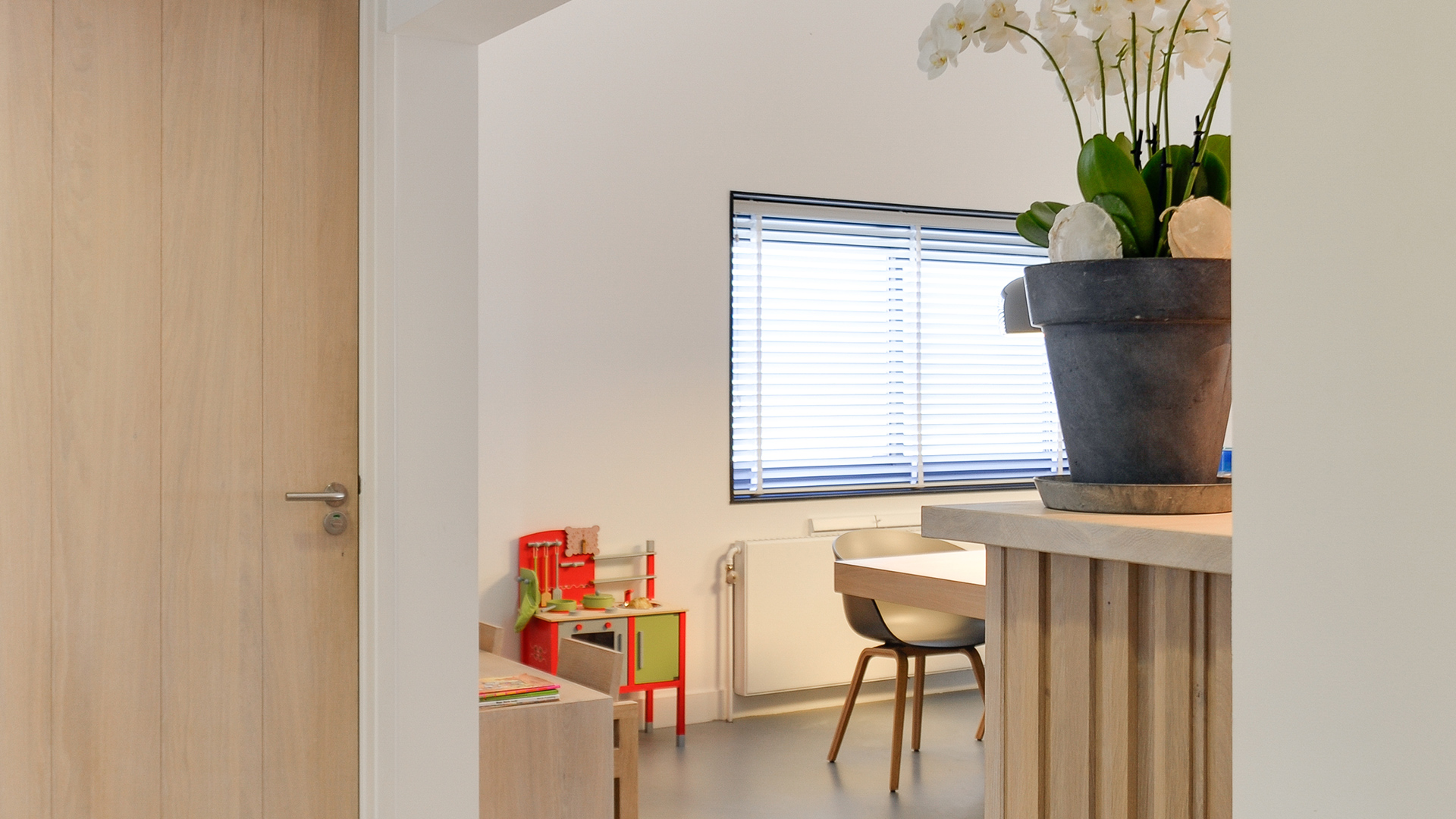 Zijkant van wachtruimte met kinderhoek en bloemen bij Tandarts Heerhugowaard