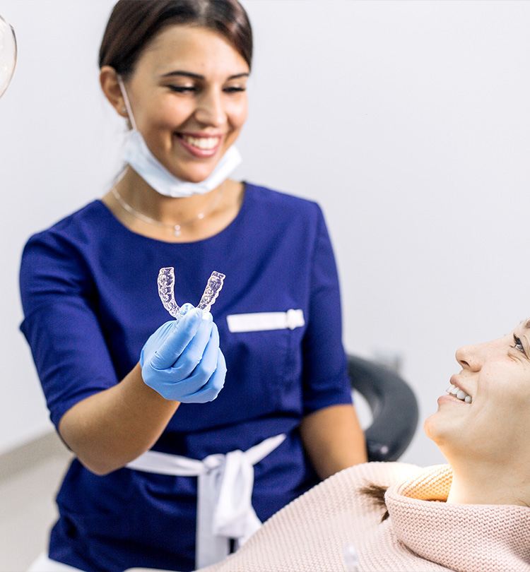 Tandartsassistent toont een Invisalign beugel aan patiënt in de stoel