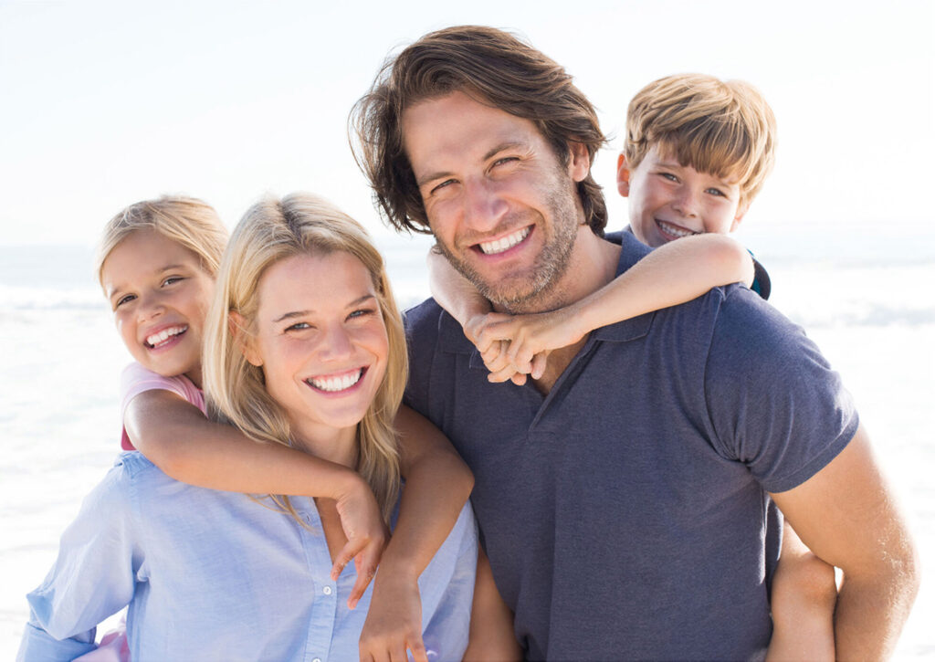 Gezin glimlacht op het strand als illustratie voor de nieuwe tandartspraktijk van Tandheelkundig Centrum Nederland in Haarlem