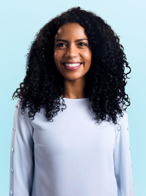 Vrouw met krullend haar lacht en toont een mooi gebit na orthodontiebehandeling