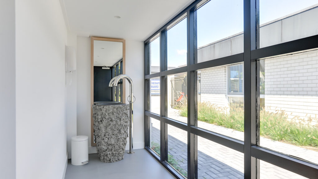 Houten gang met natuurstenen wasbak en spiegel bij Tandarts Heerhugowaard