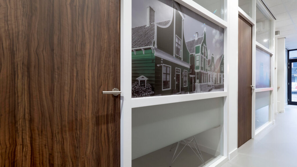 Hal met behandelruimtes in Tandarts Westzaan met foto van Zaanse huizen op de wand