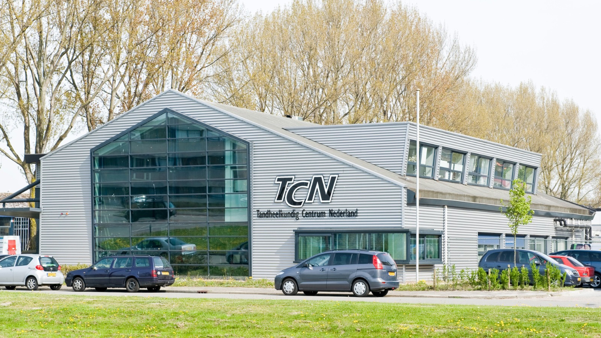 Voorzijde van het moderne TCN-gebouw met glasgevel en logo van Tandarts Alkmaar Oudorp