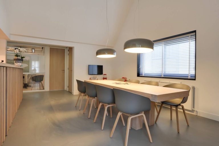 Moderne wachtruimte met lange tafel en designstoelen bij Tandheelkundig Centrum Nederland in Heerhugowaard